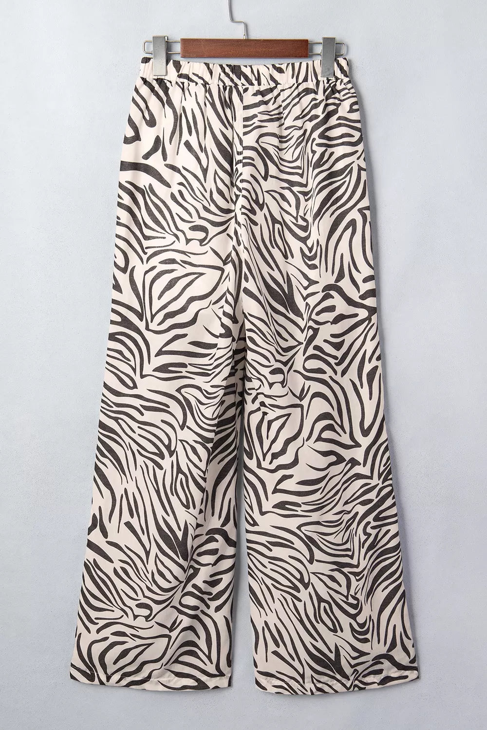 Zebra print drawstring pants on a hanger, angled view of the wide legs