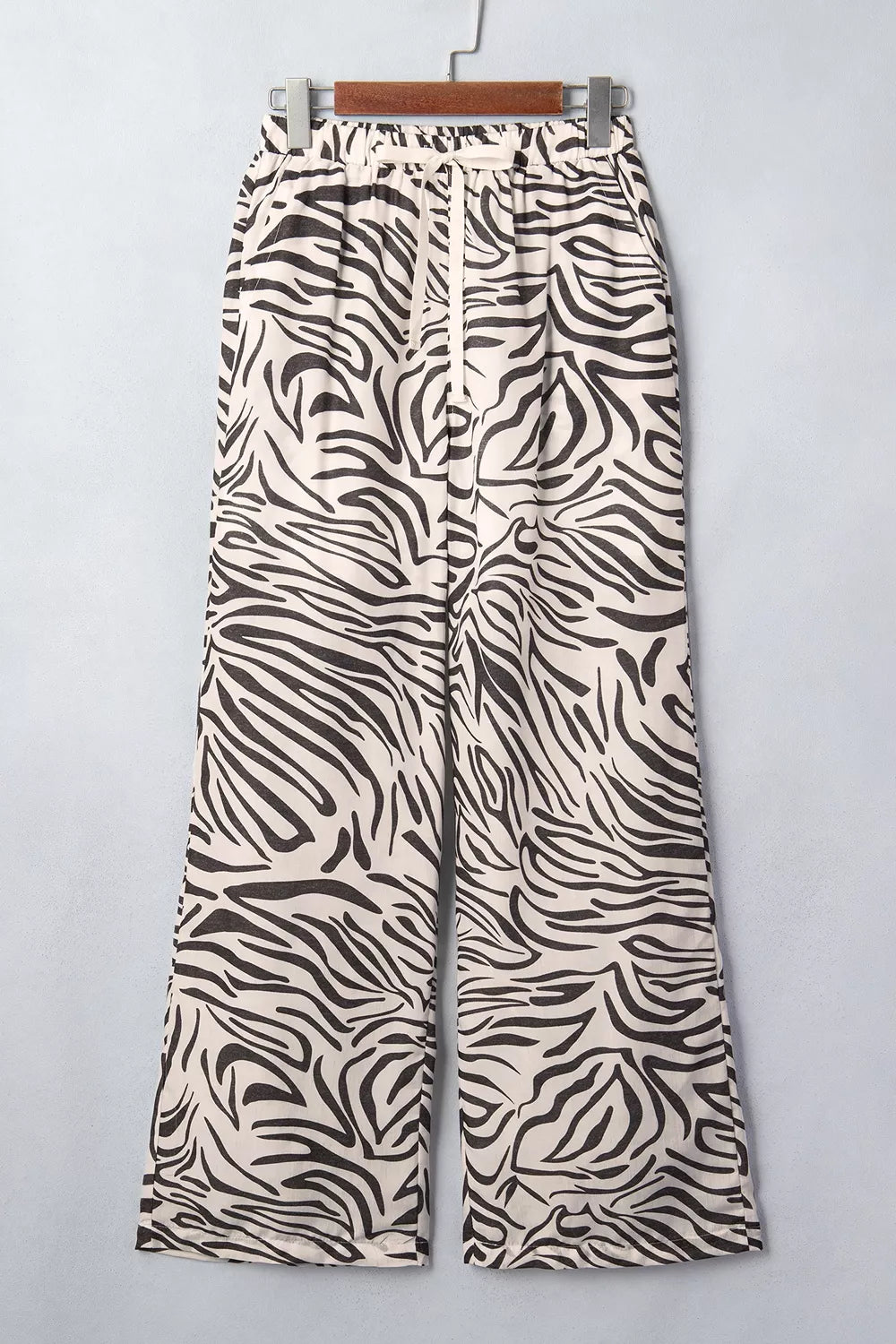 Zebra print wide leg pants hanging on a hanger, front view