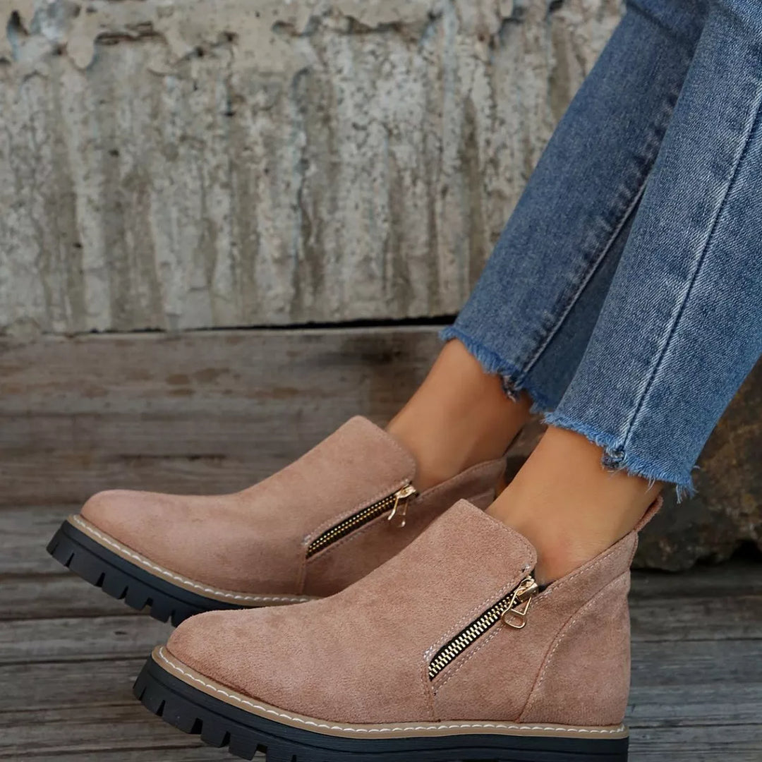 Dusty rose lug sole ankle boots from a low side angle with zipper detail