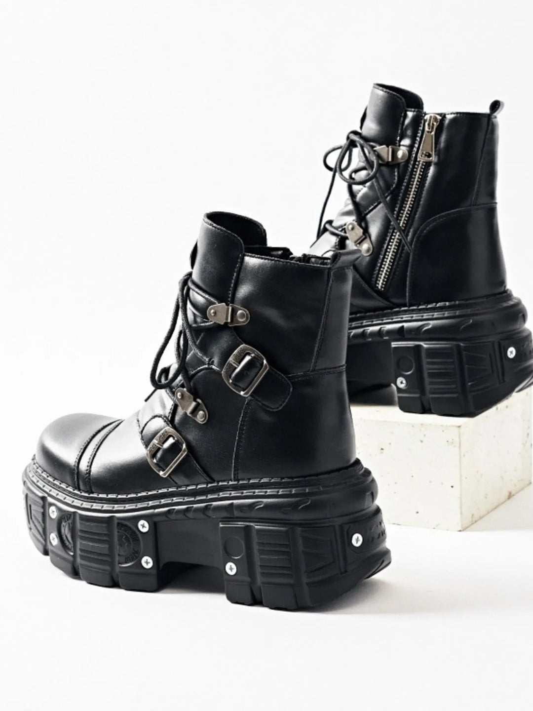 Black chunky platform ankle boots, one upright and one resting on a block