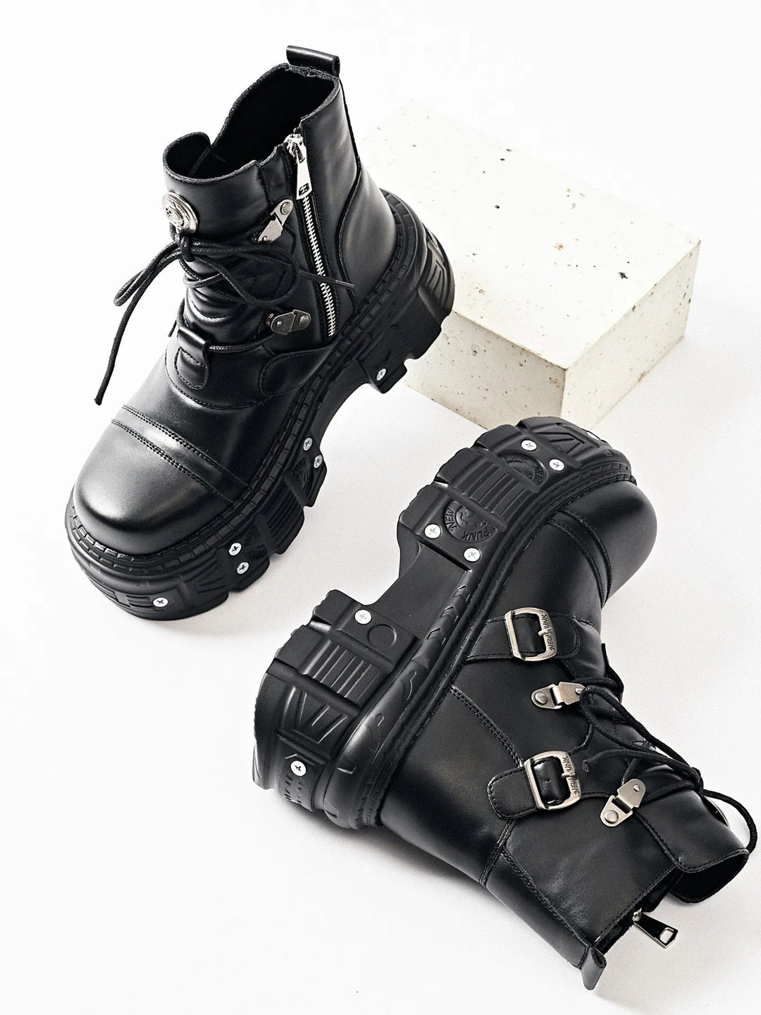 Black buckle ankle boots with side zipper, one boot tipped on its side