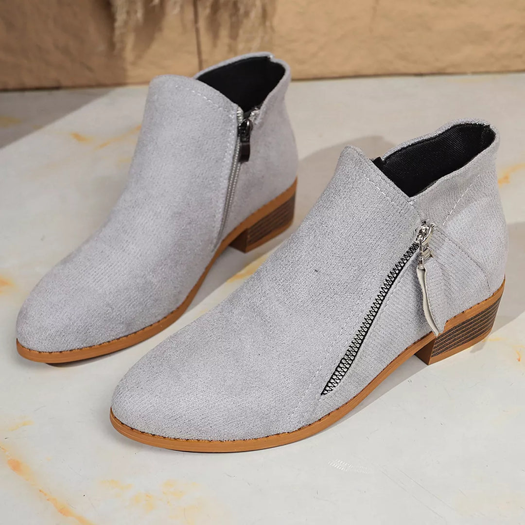 Pair of light gray ankle boots with pointed toe on a pale floor