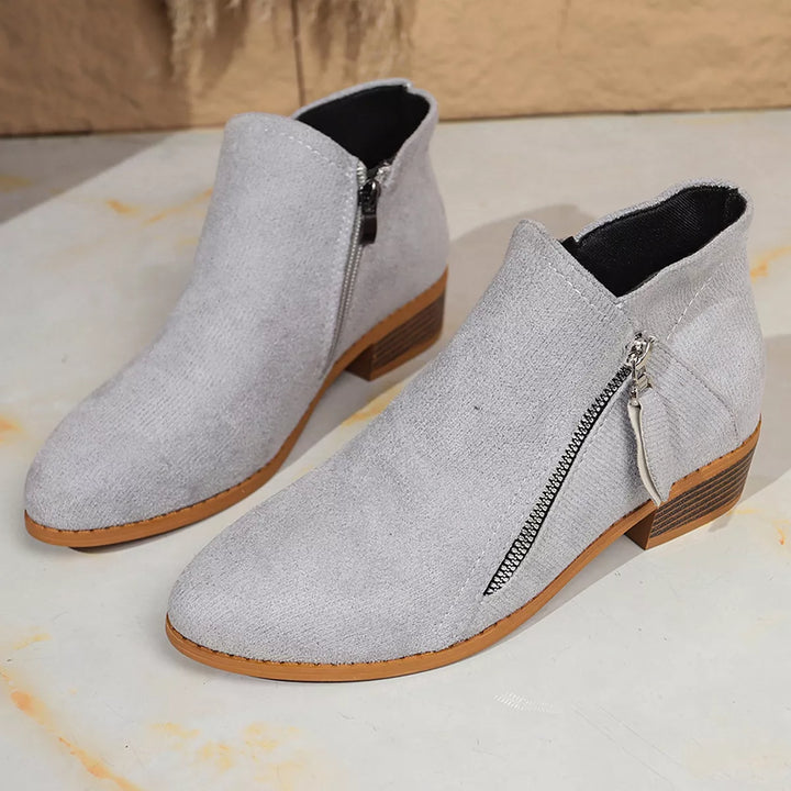 Pair of light gray ankle boots with pointed toe on a pale floor