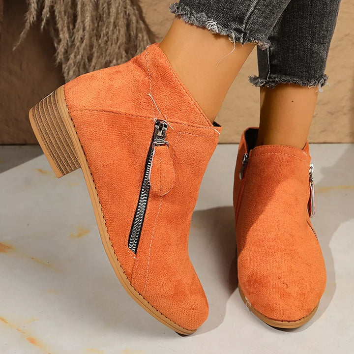 Orange ankle boots with side zip worn with cuffed jeans, angled view