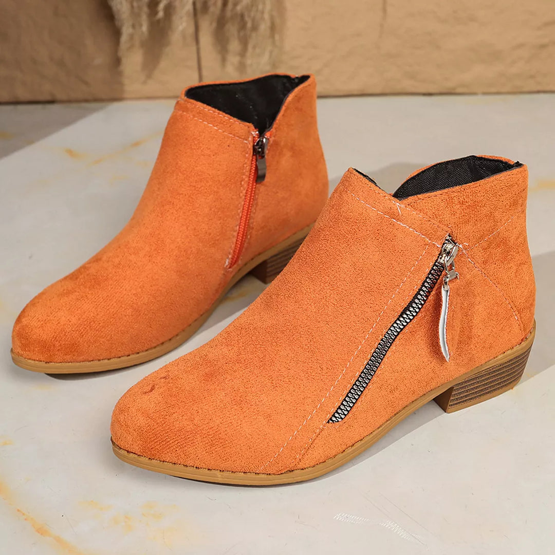 Pair of orange pointed toe ankle boots with diagonal zip