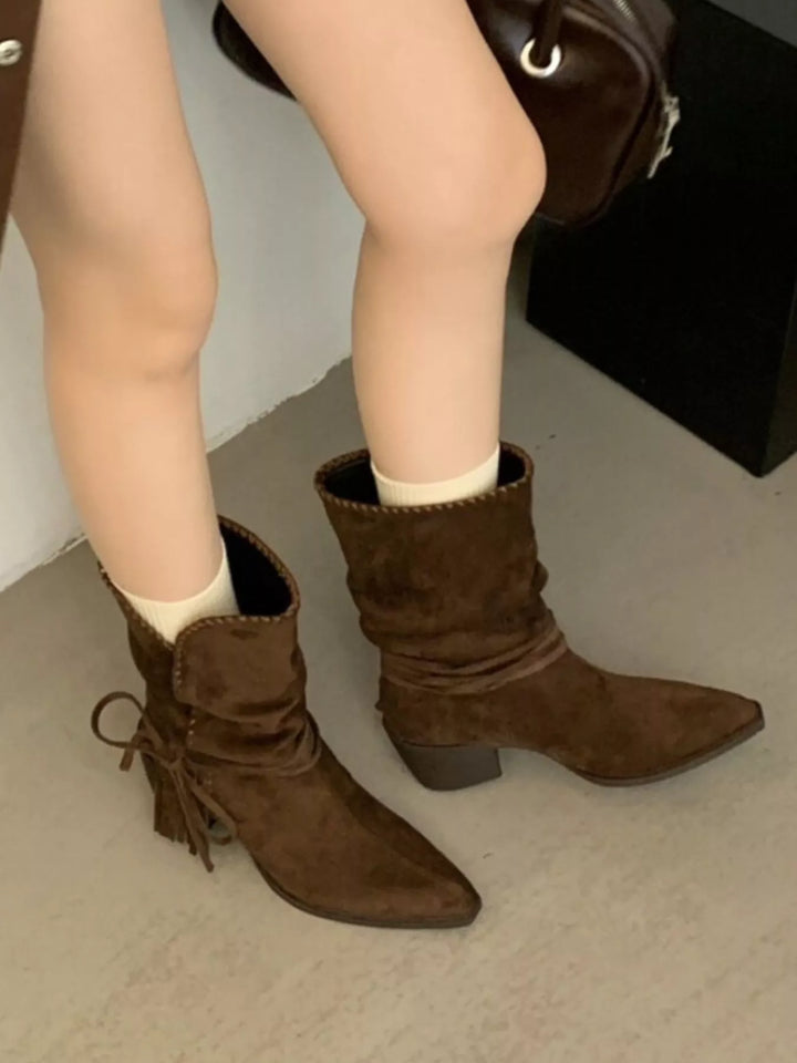 Dark brown pointed toe ankle boots worn with cream socks, seated pose