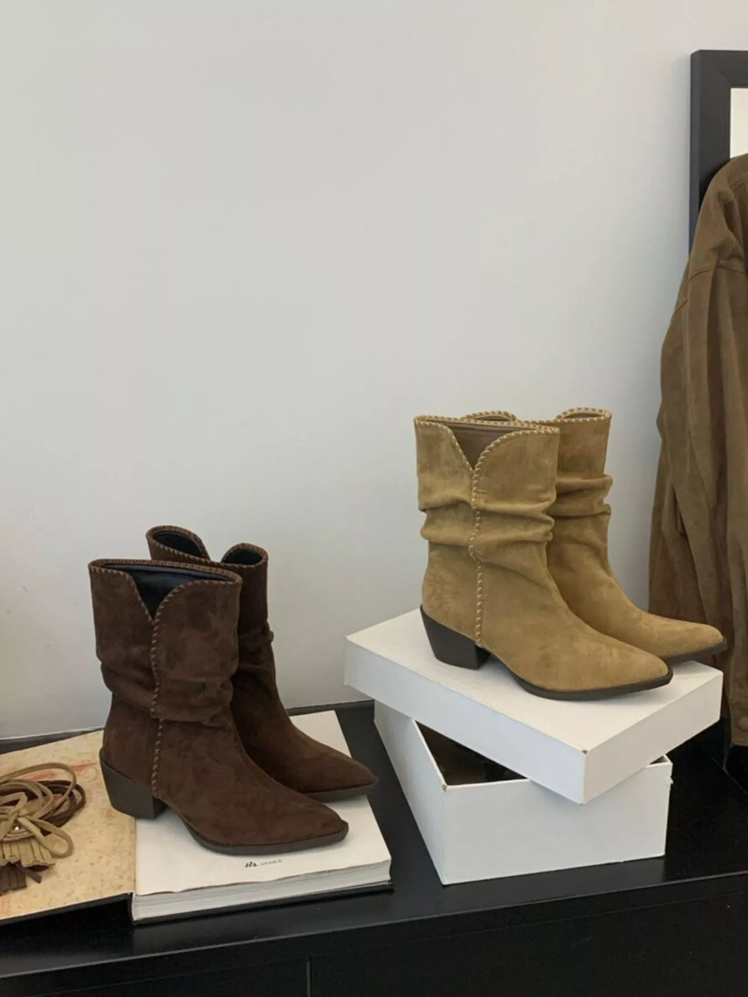 Tan and dark brown slouchy ankle boots displayed side by side on a stand