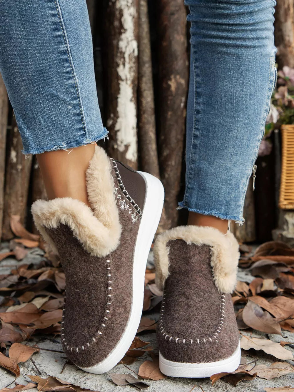 Brown slip on ankle boots with a fur-look cuff and white sole, front view