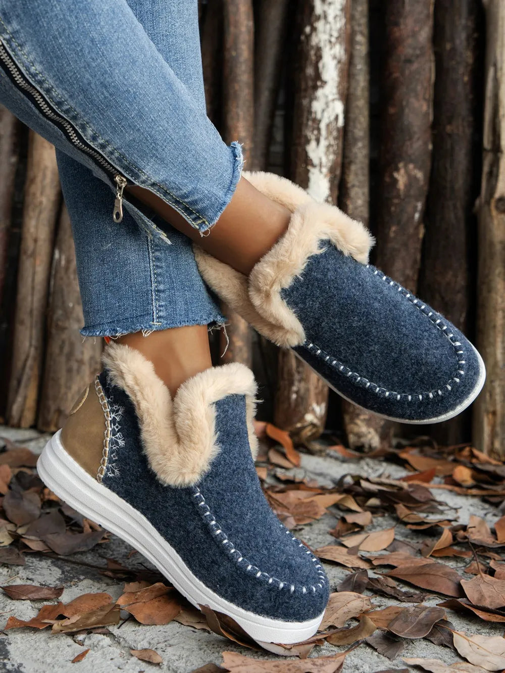 Navy slip on ankle boots with studded stitching and fur-look cuff, worn with jeans