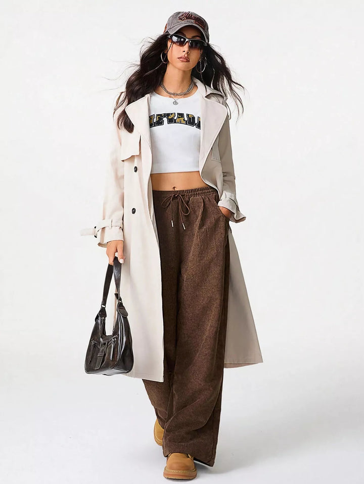 Brown baggy pants styled with a white crop top and beige trench coat