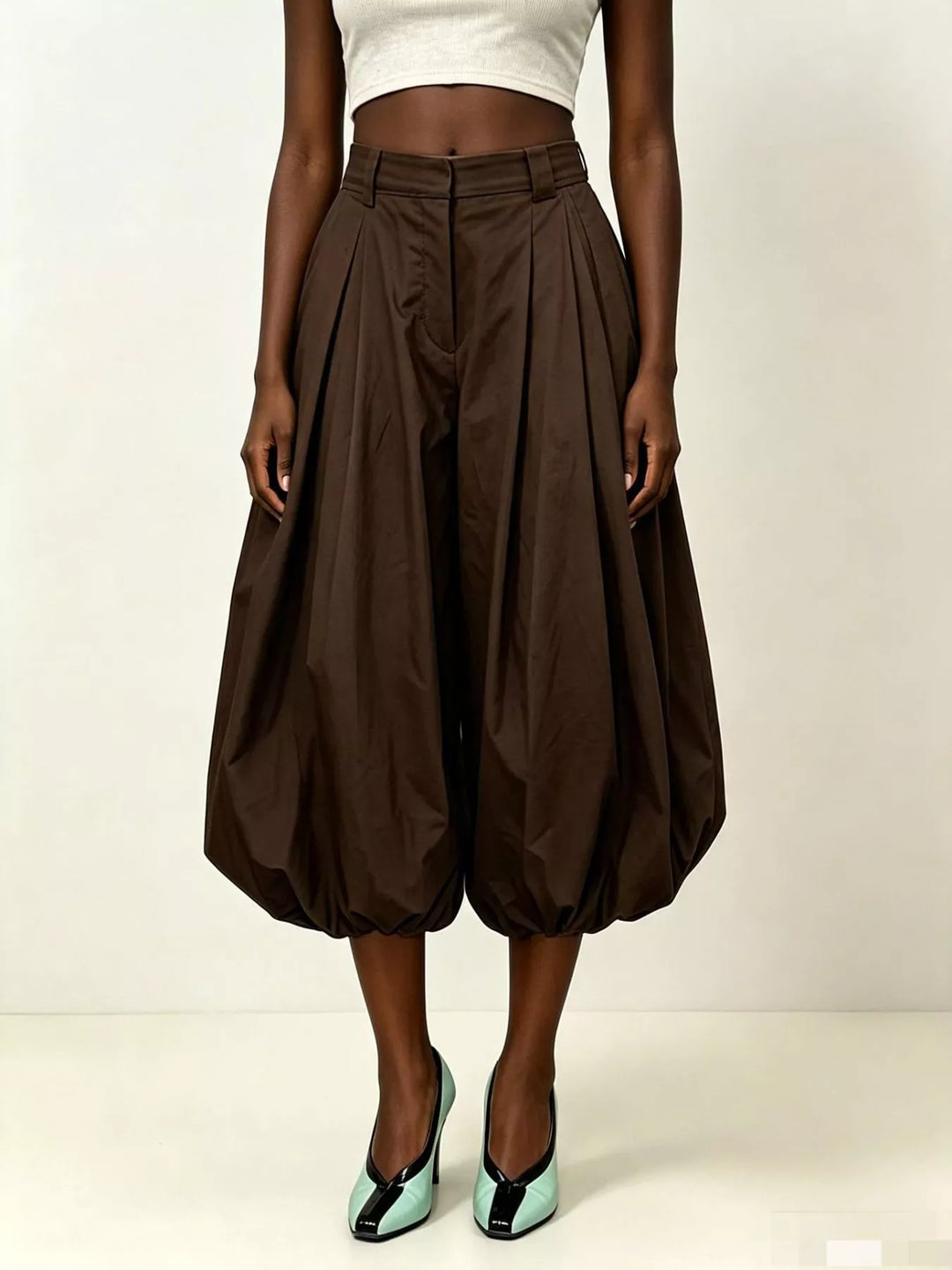 Brown pleated balloon pants worn with a cropped top and green heels