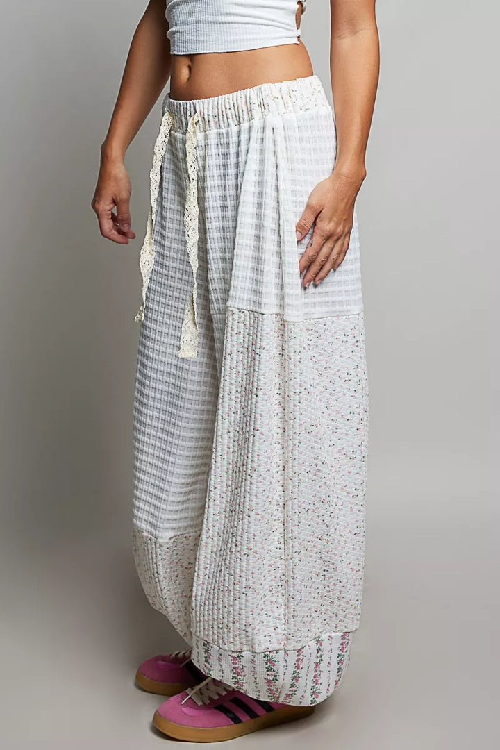 Ivory patchwork balloon pants seen from a slight angle with drawstring waist