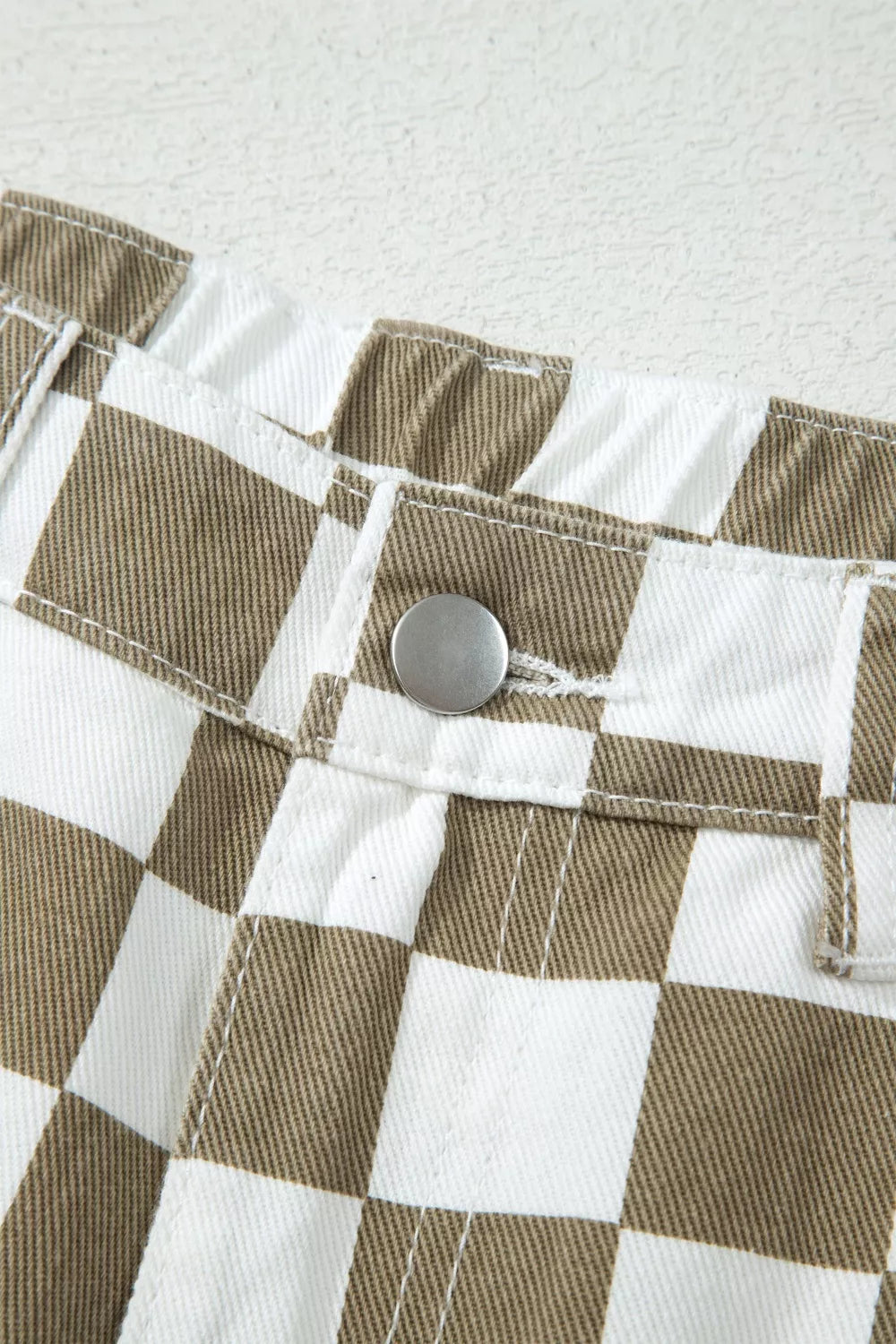 Close-up of the button closure on the khaki checkerboard pants