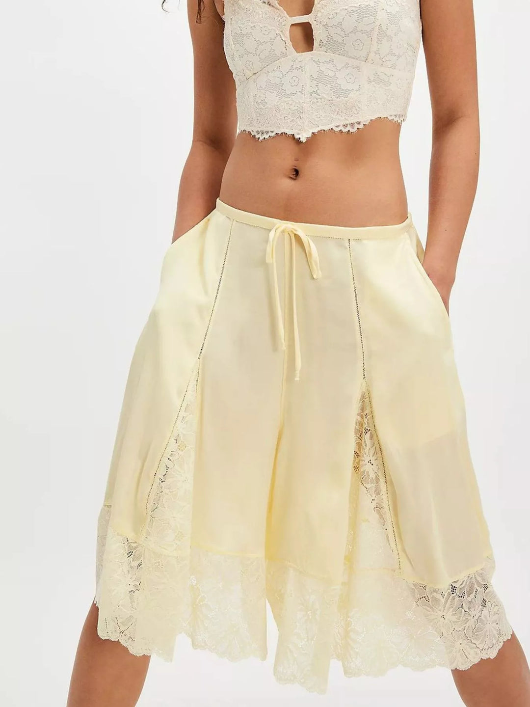Pastel yellow Bermuda shorts with lace inserts styled with a lace bralette