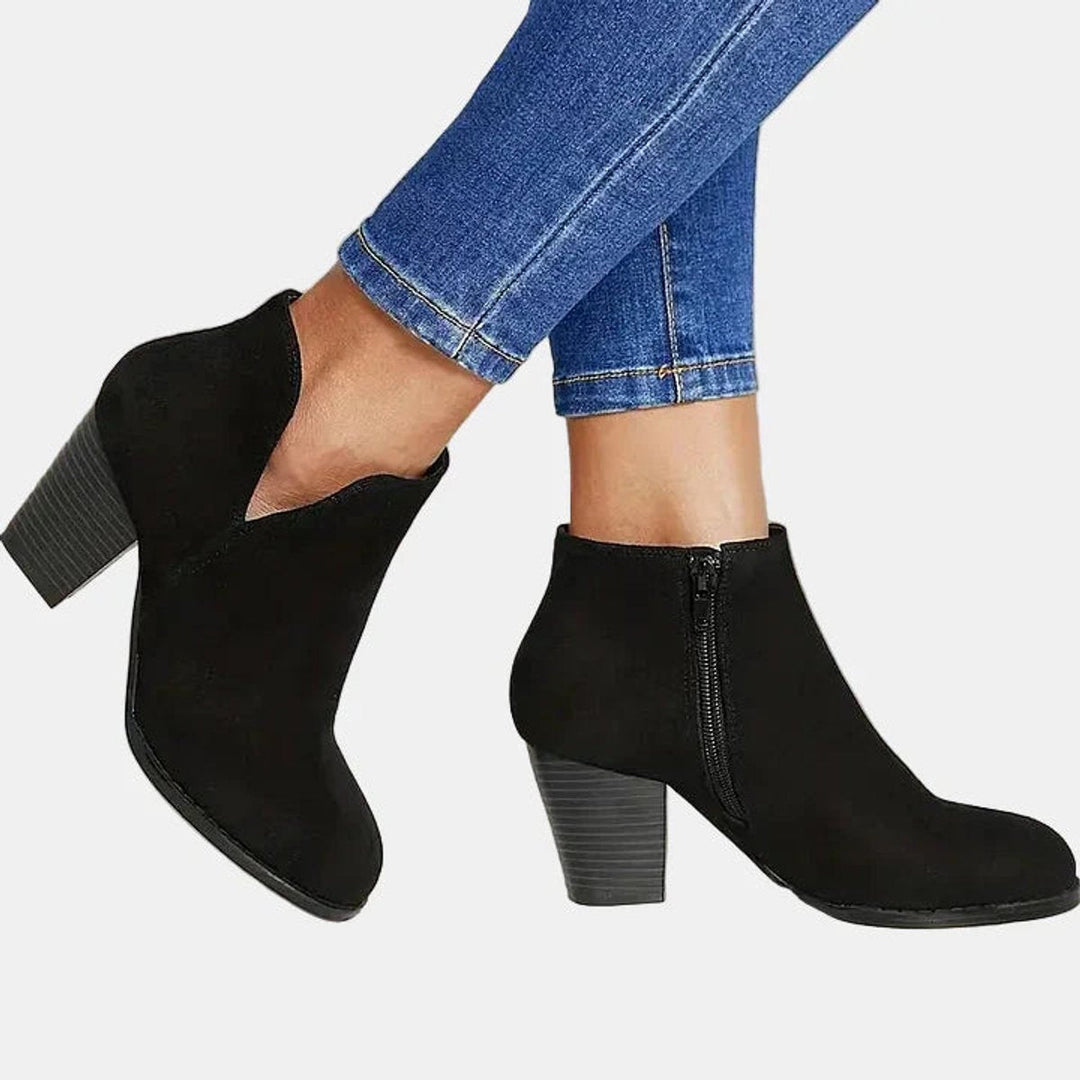 Black block heel booties in motion showing the inner side zip
