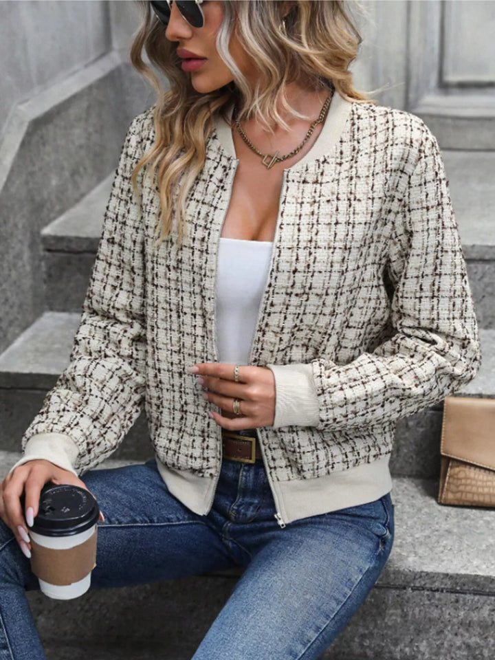 Women's cream cropped bomber jacket in plaid tweed look, zip up, seated on steps