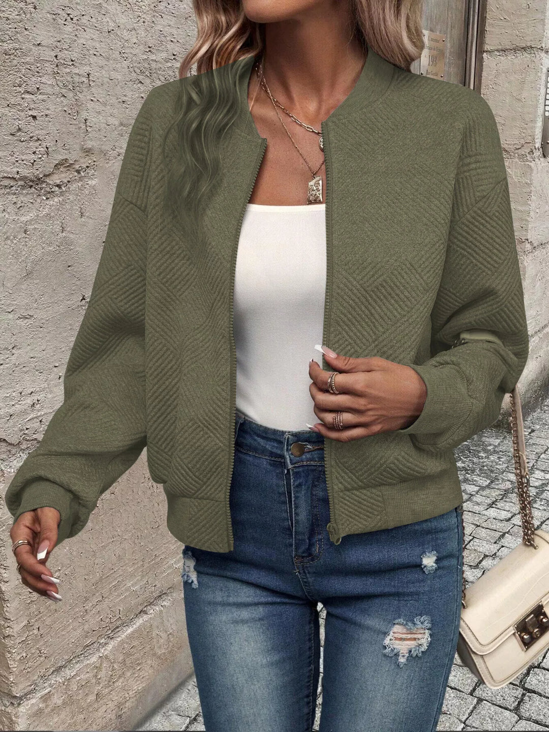 Close-up of the olive green bomber jacket open with ribbed hem
