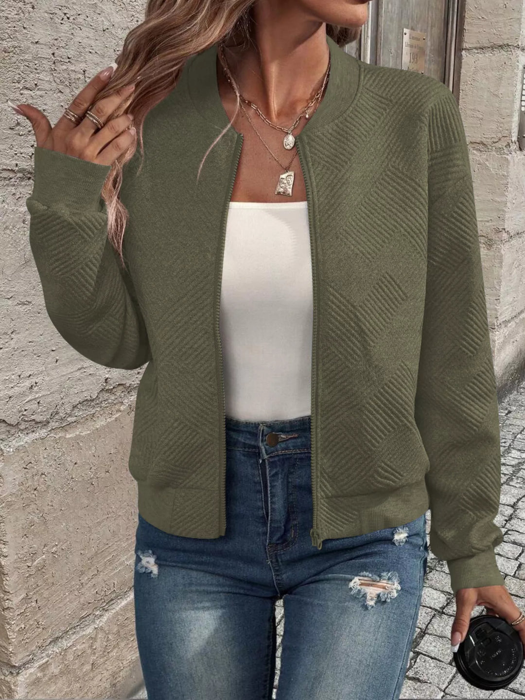 Olive green quilted bomber jacket worn open over a white top