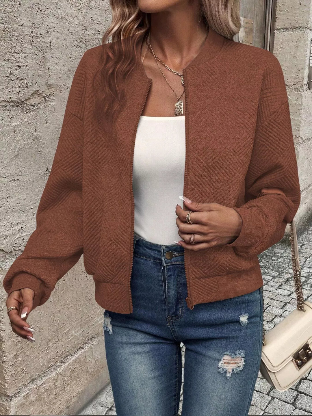 Rust brown cropped bomber jacket worn open in a walking pose