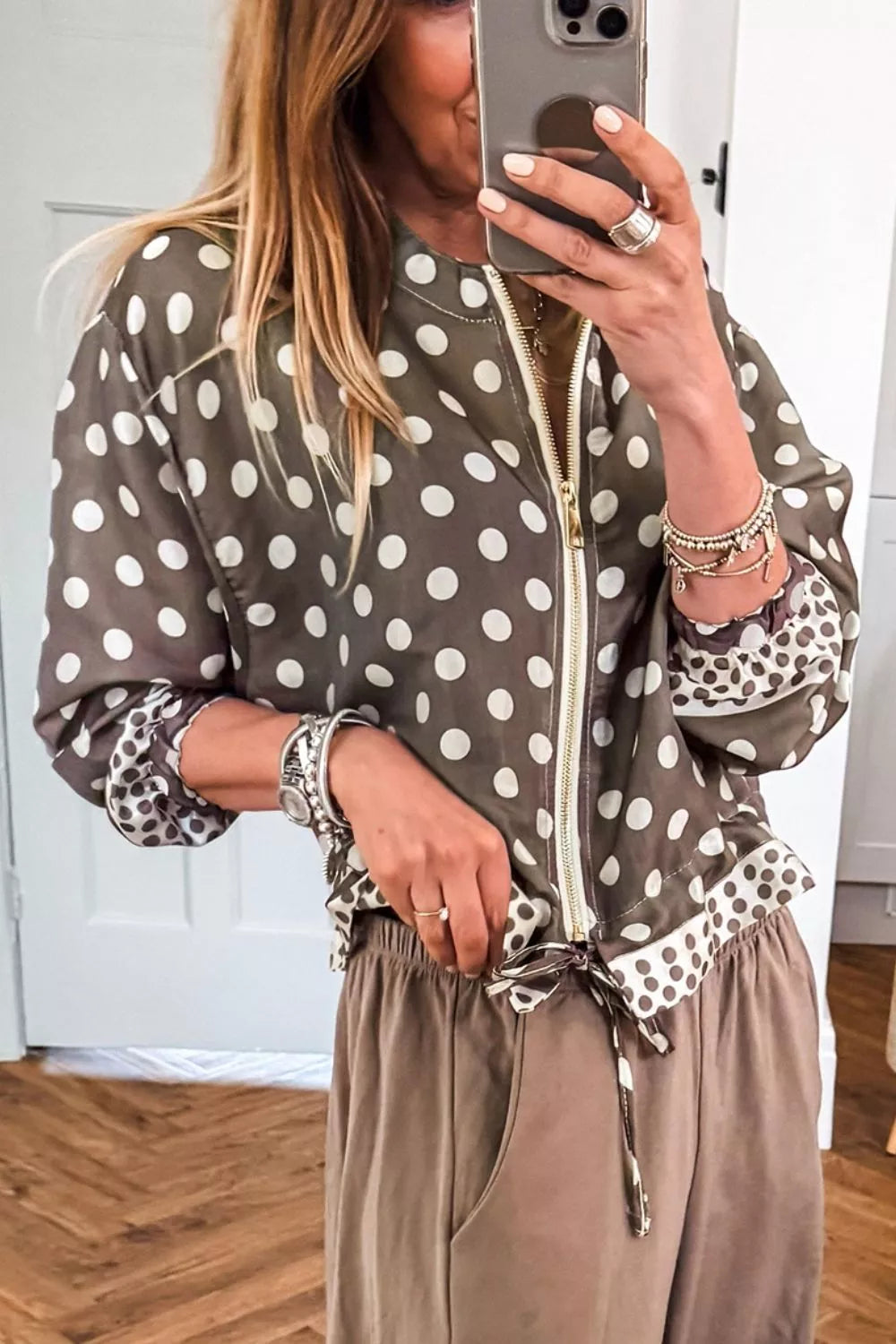 Taupe polka dot bomber with printed cuffs, styled with beige drawstring pants