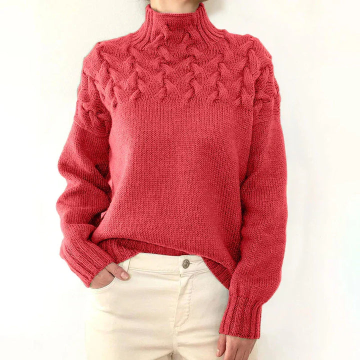 Model wearing the coral cable knit sweater with a mock neck and twisted cable yoke