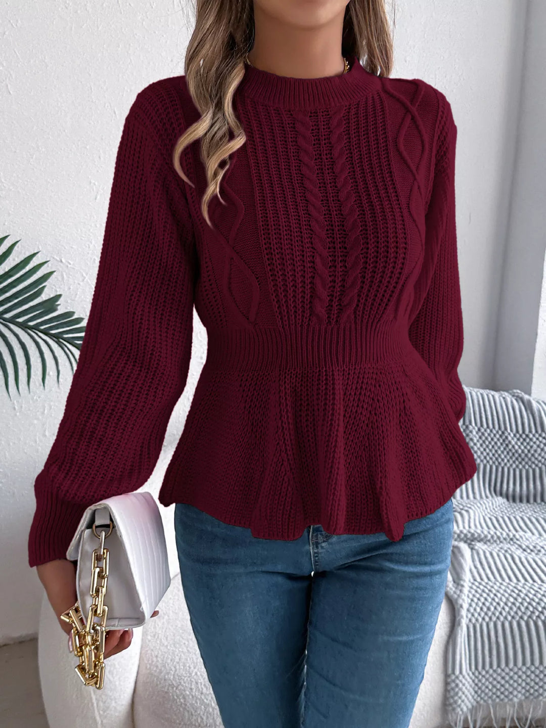 Burgundy cable knit sweater with peplum ruffle hem, front view with clutch