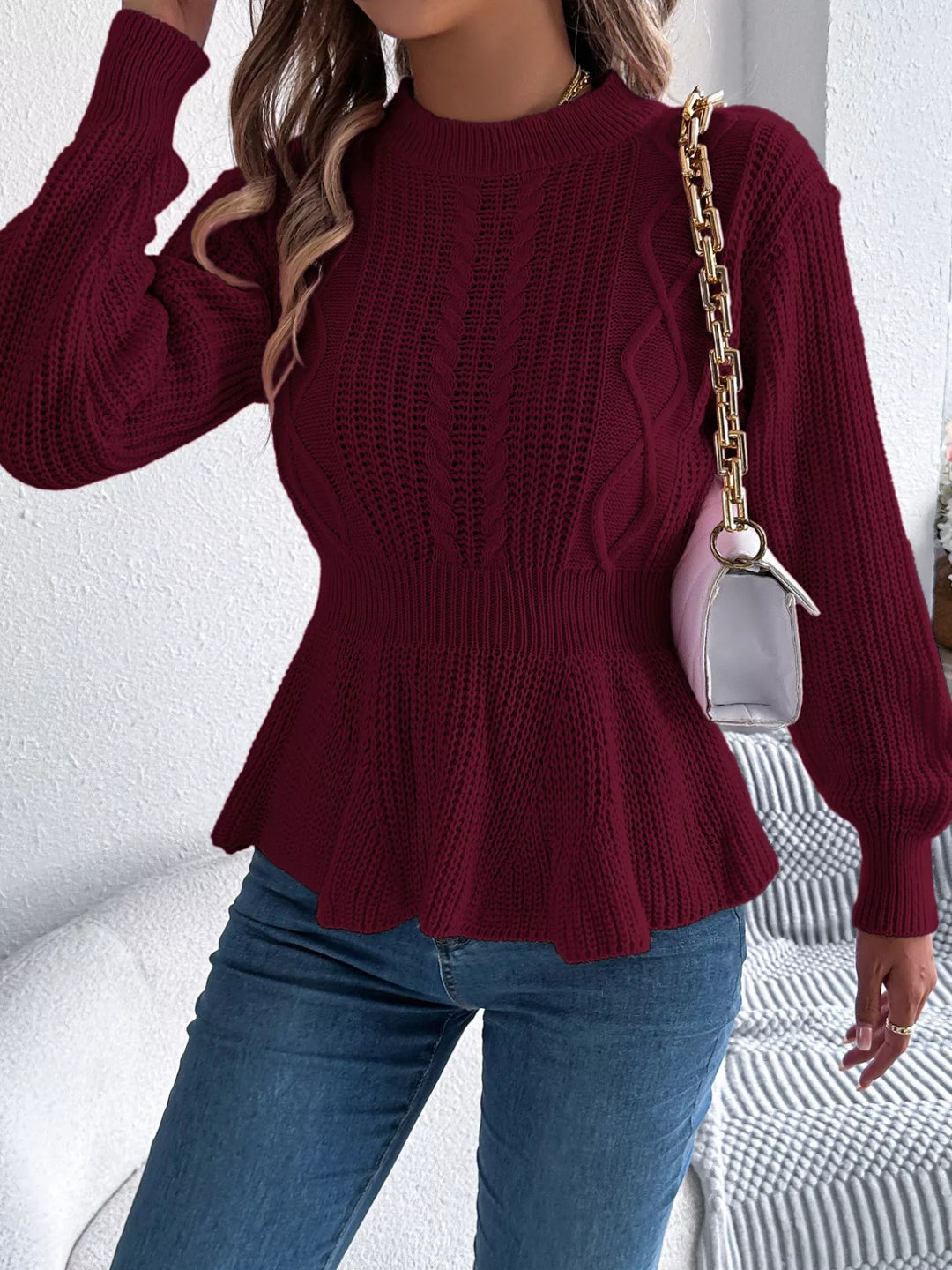 Burgundy cable knit sweater with chain strap bag and blue jeans
