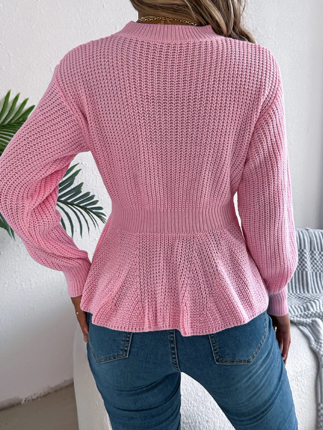Back view of the pink cable knit sweater with ribbed peplum hem
