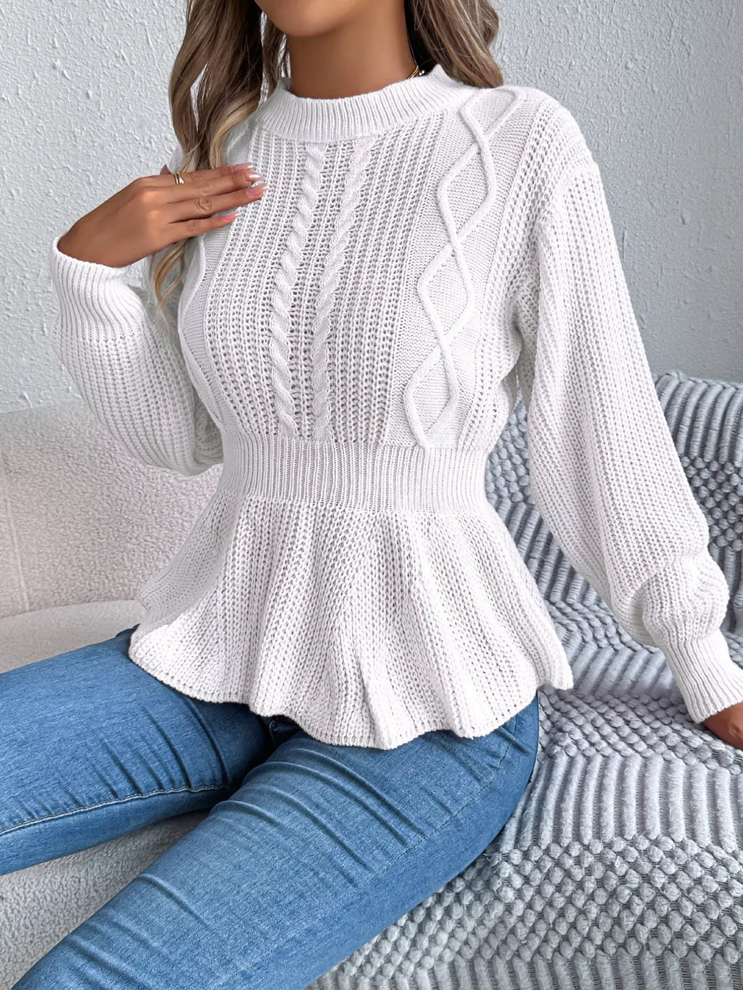 White peplum sweater worn with jeans, hand raised to the collar