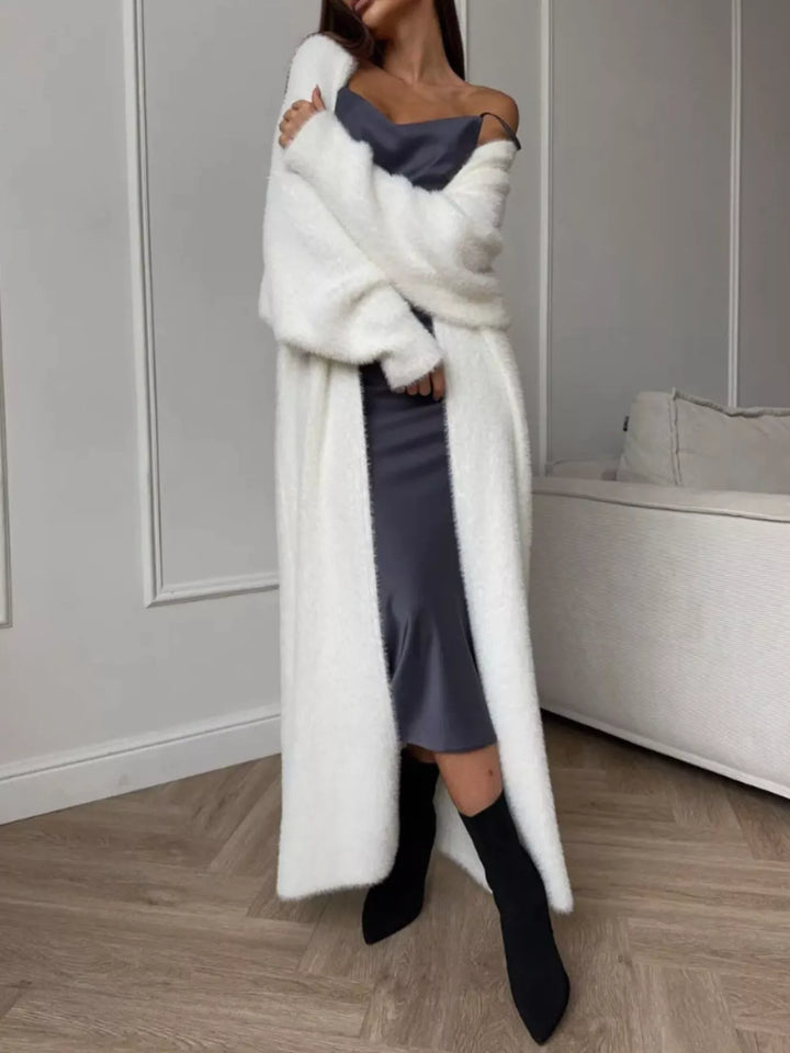 Ivory longline cardigan angled view with boots on a wood floor