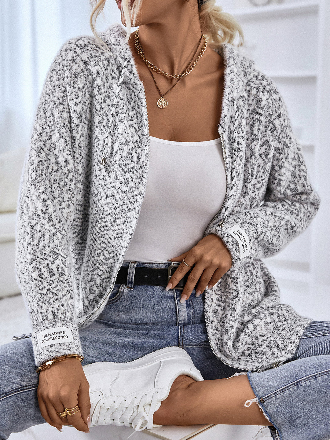 Heather gray zip cardigan worn open with jeans while seated