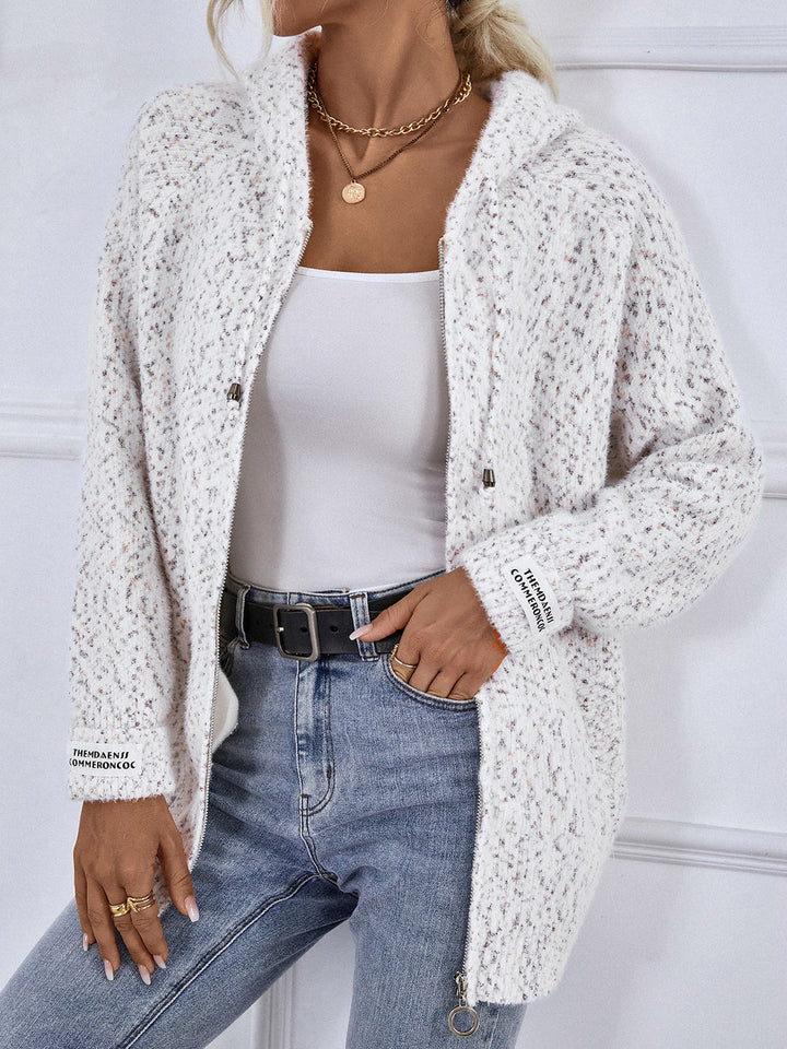 White zip front cardigan worn open with a hand in the pocket