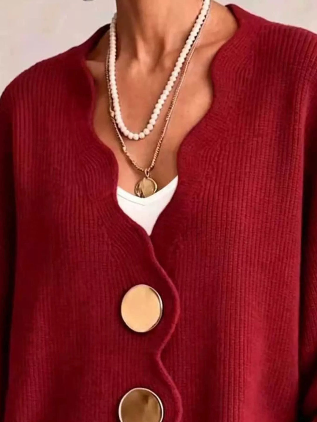 Close-up of the red cardigan wavy neckline layered with pearl necklaces