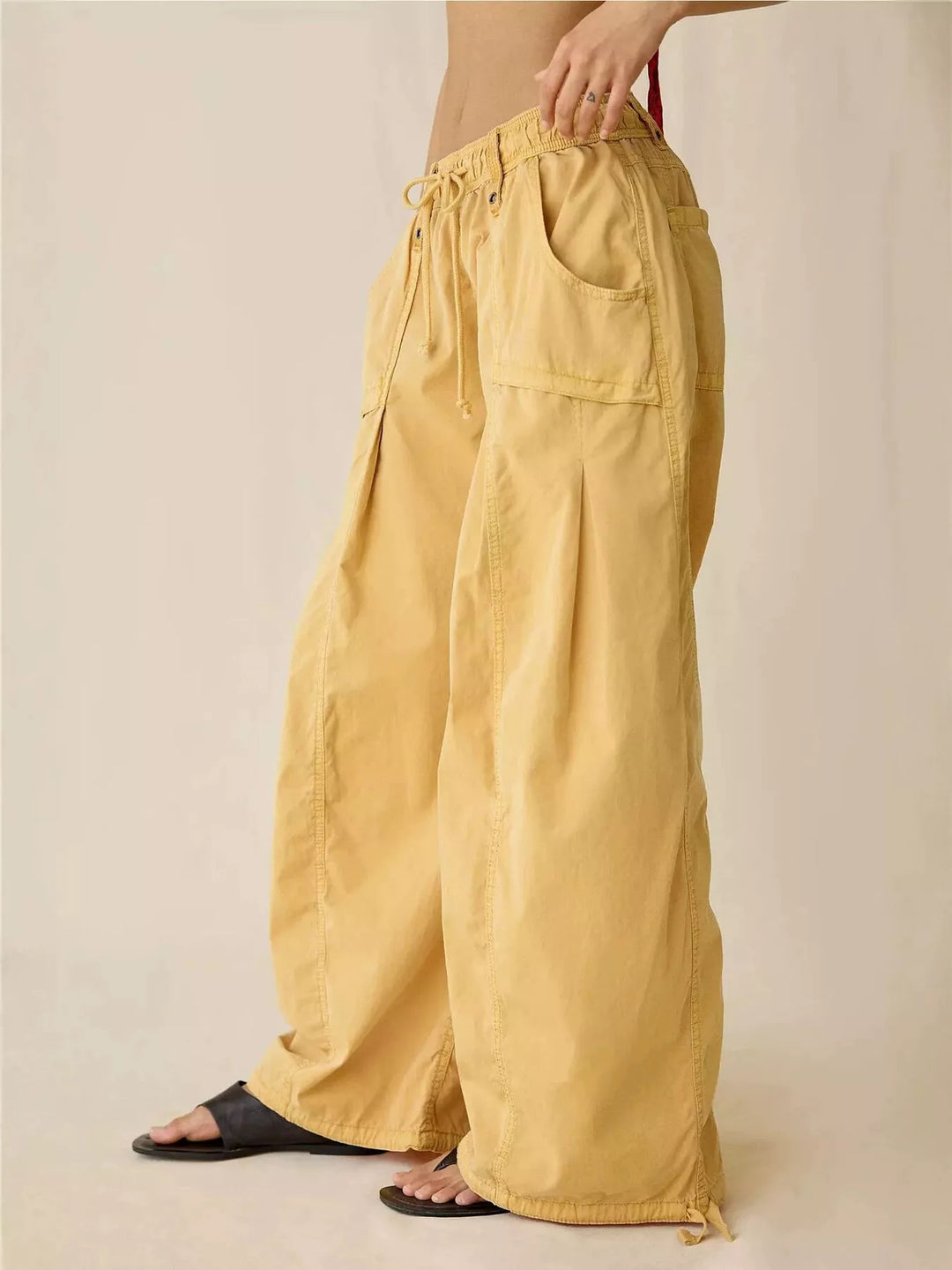 Mustard parachute cargo pants in side view with black sandals