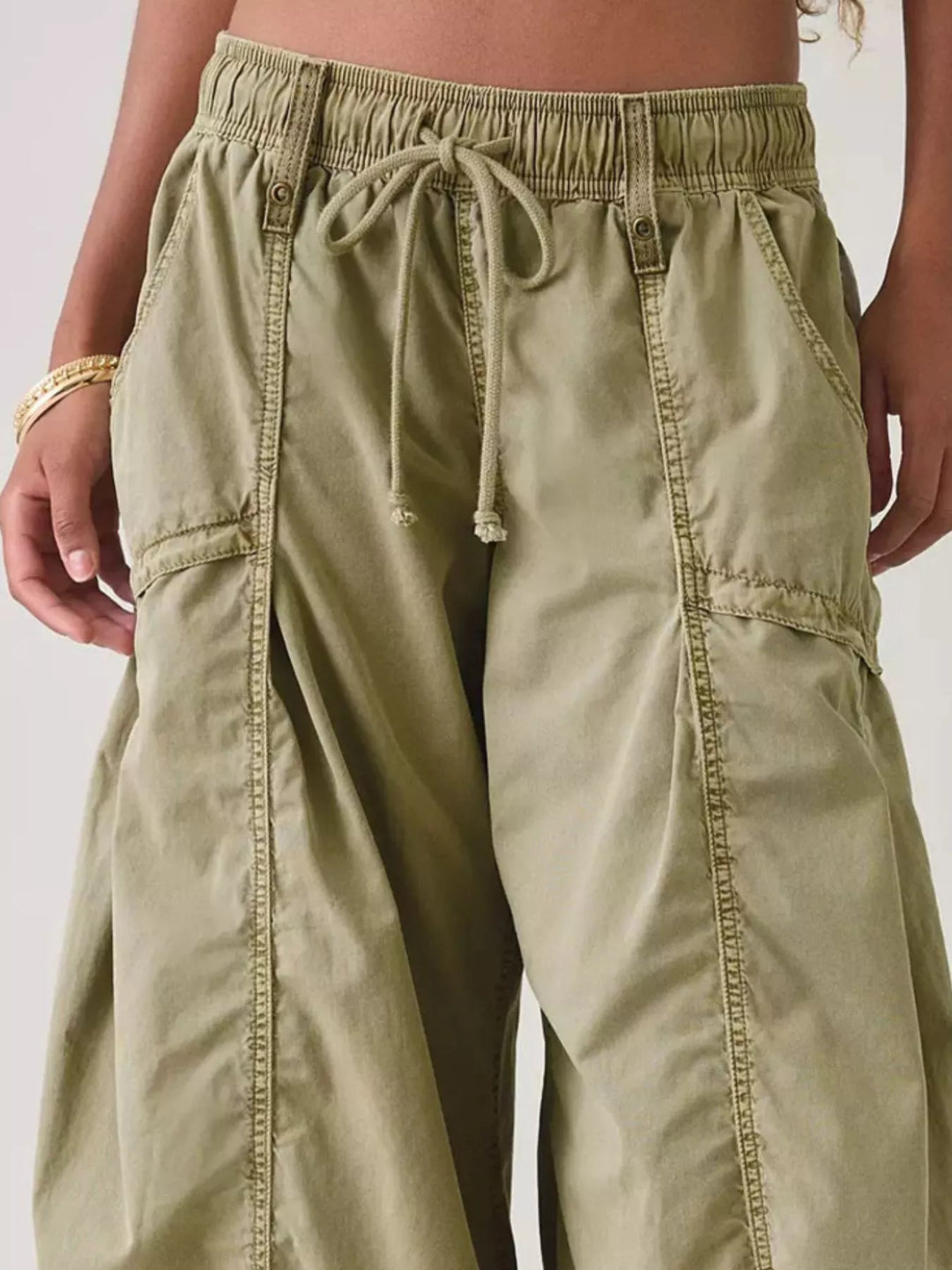 Close-up of sage cargo pants waistband, drawstring and cargo pocket