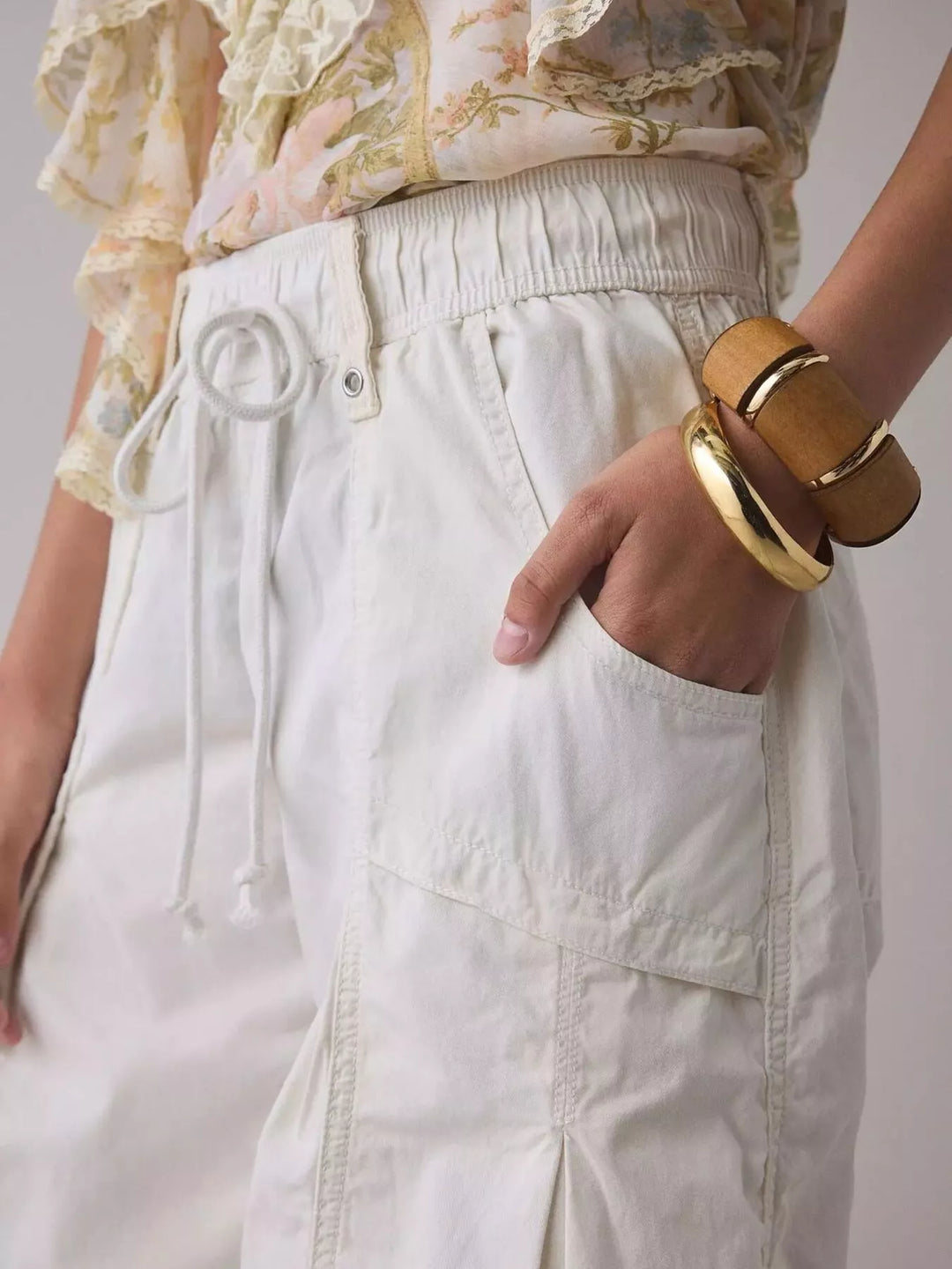 White parachute cargo pants with hand in pocket, close-up of drawstring and cargo pocket