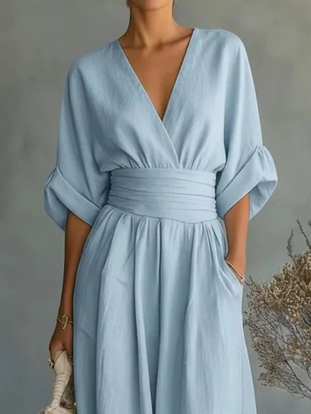 Close-up of the light blue wrap jumpsuit with a cinched waist and rolled sleeves