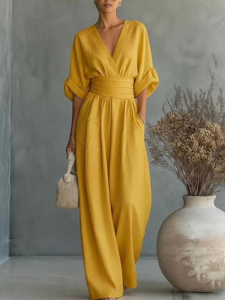 Mustard casual jumpsuit with a deep V neck and wide legs, holding a small bag
