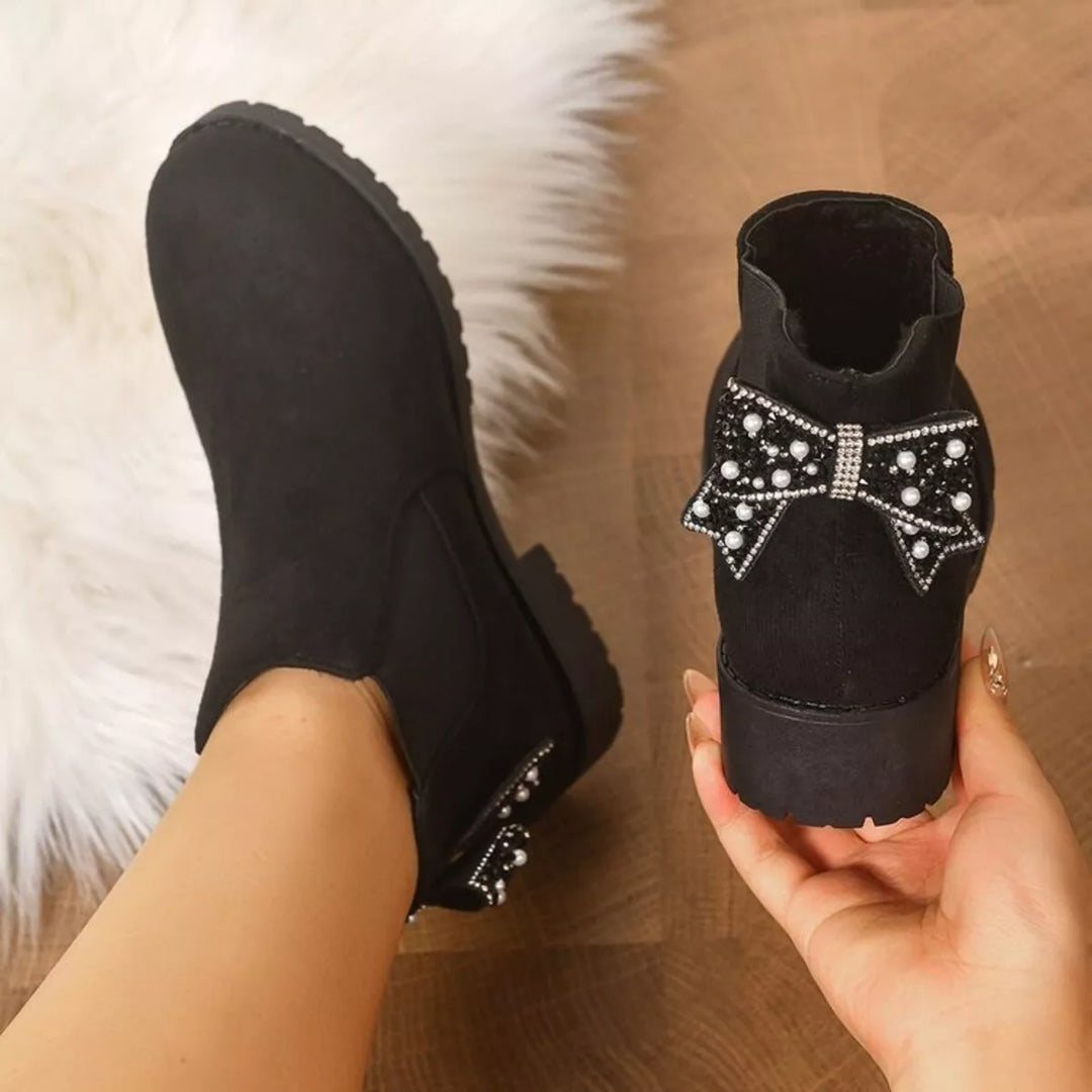 Black Chelsea boots with a pearl bow at the heel, back view