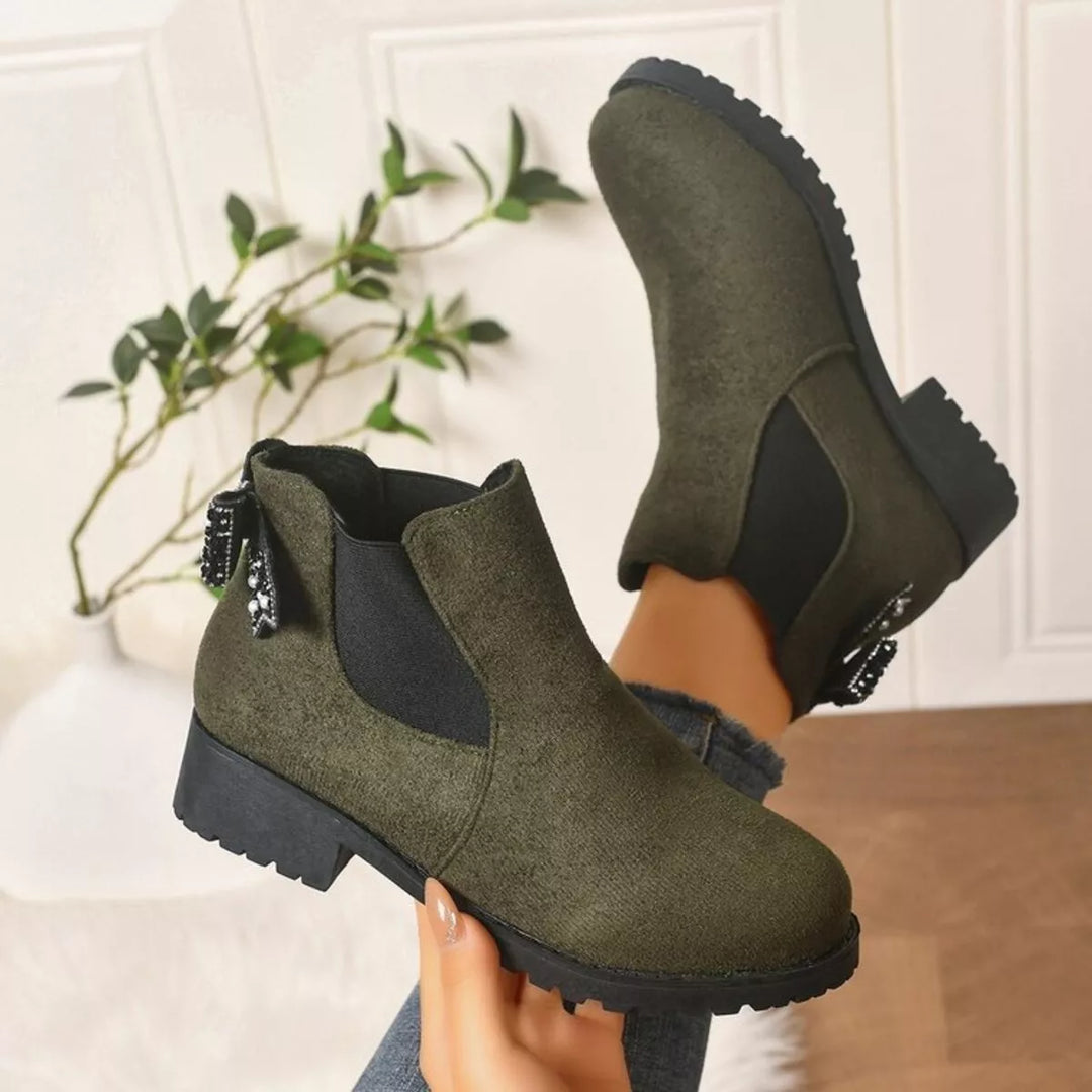 Olive Chelsea boots with block heel and lug sole, held in hand
