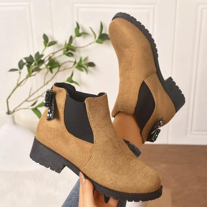 Tan Chelsea boots with lug sole and elastic gore, held in hand