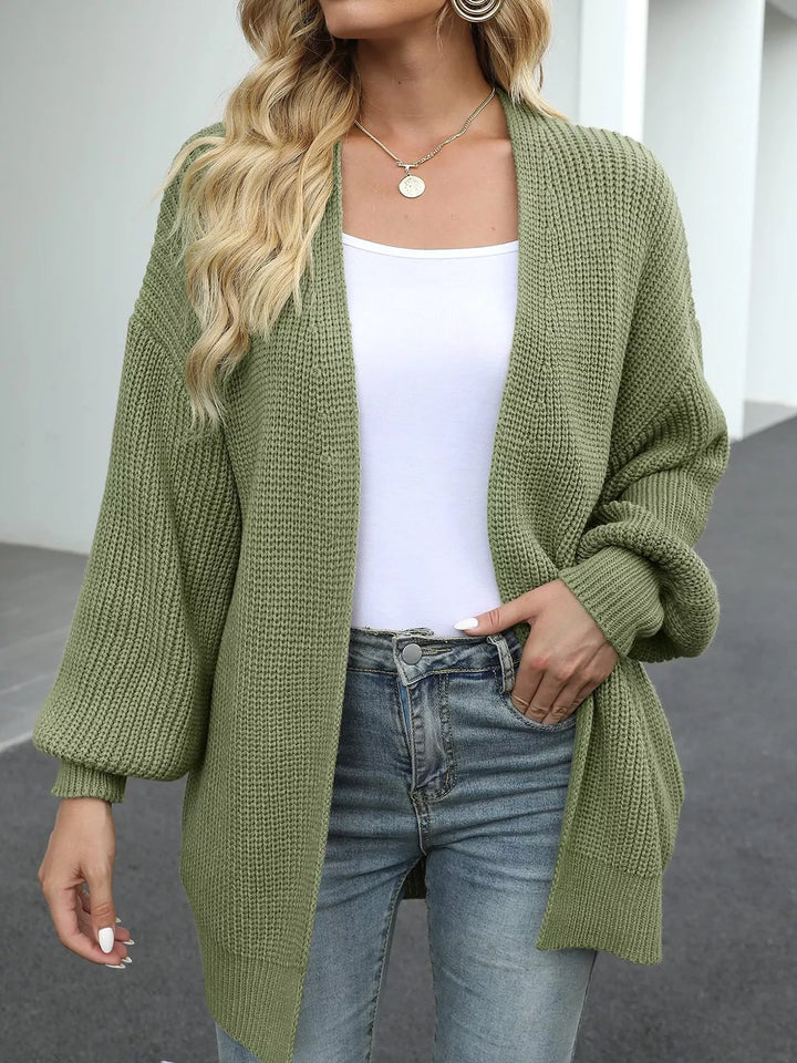 Front view of the sage green chunky knit cardigan with a hand in the pocket