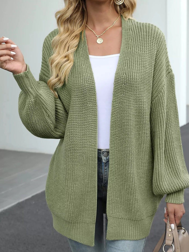 Sage green cardigan worn open with jeans and a small handbag