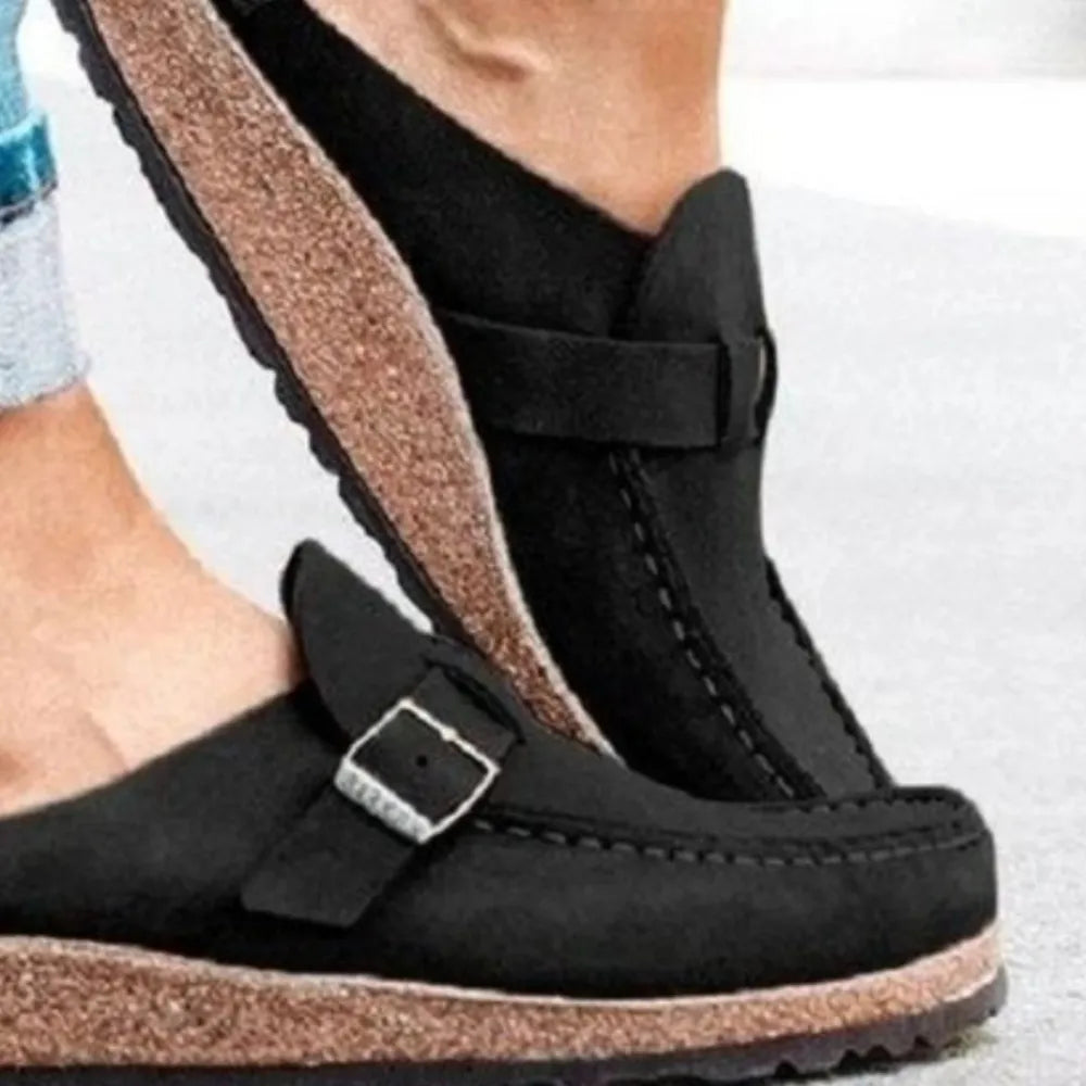 Close-up of the black slip on clog with buckle strap and cork style sole