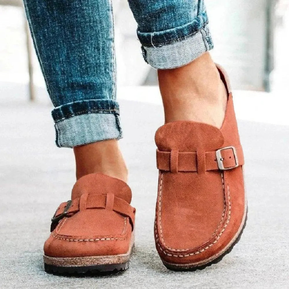 Rust slip on clogs with buckle strap worn with rolled jeans