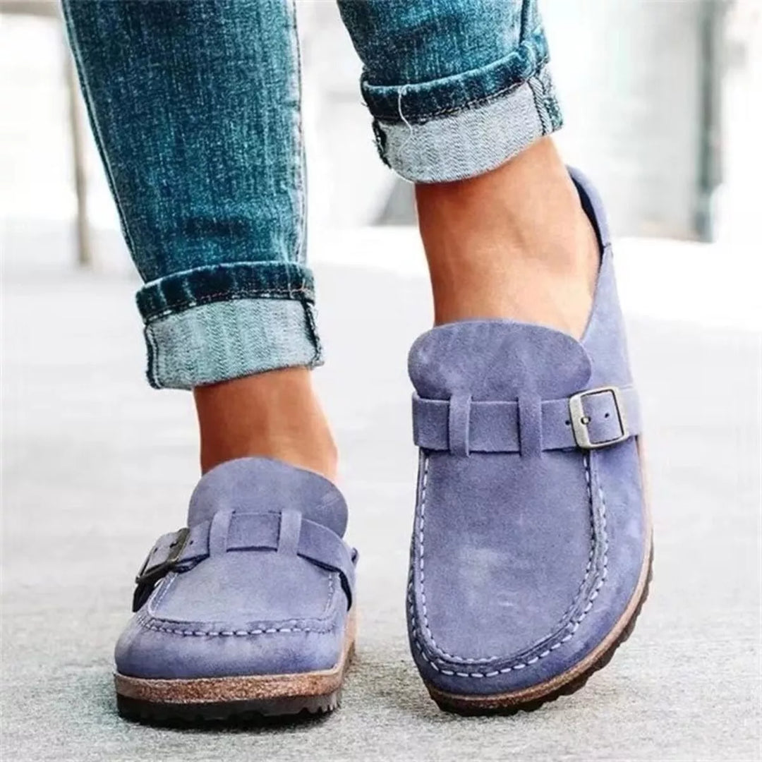 Lilac slip on clogs with buckle strap worn with rolled jeans, front view