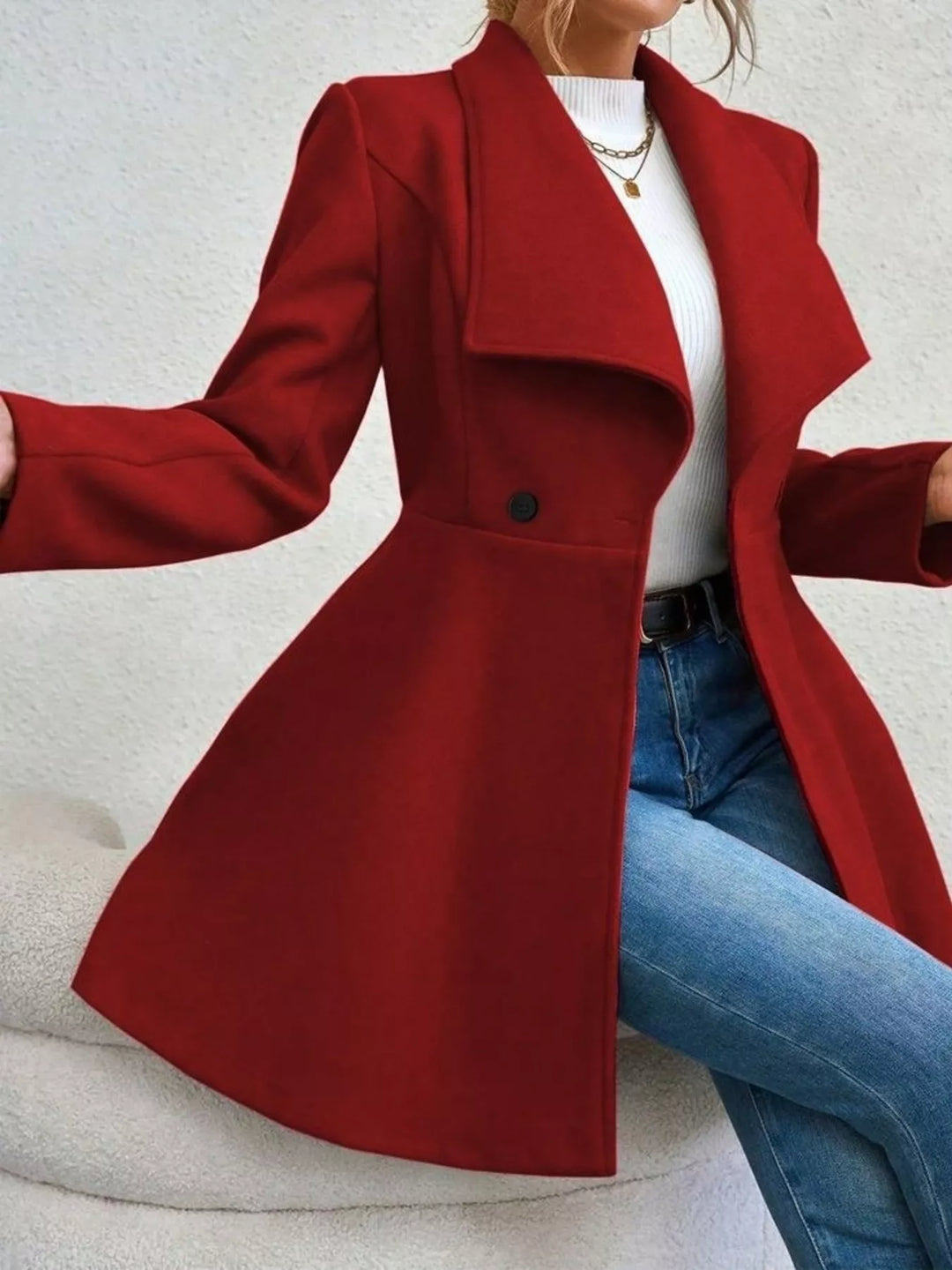 Burgundy double breasted coat in a seated pose with blue jeans