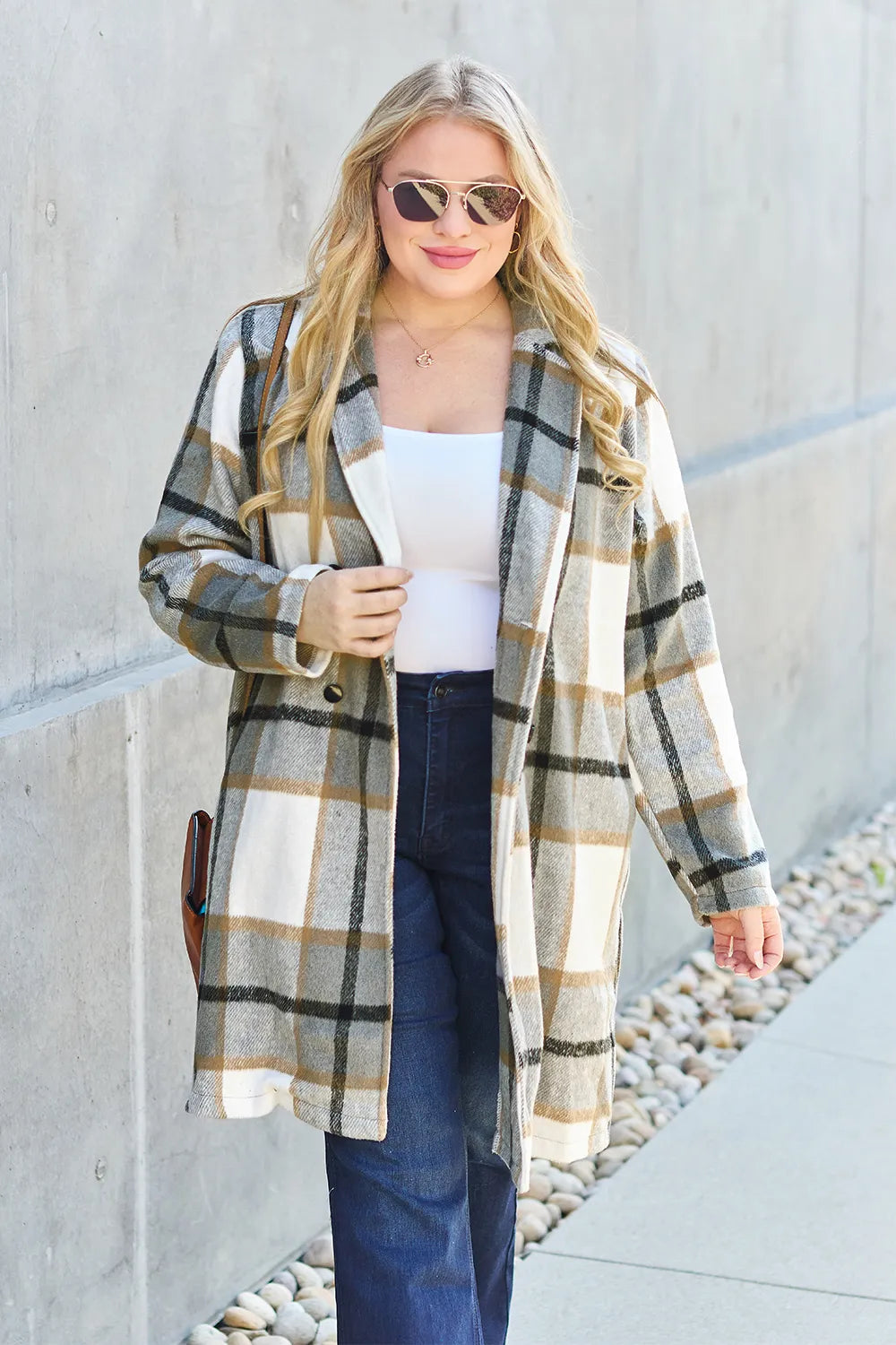 Olive plaid coat worn open over a white top with flare jeans, close framing