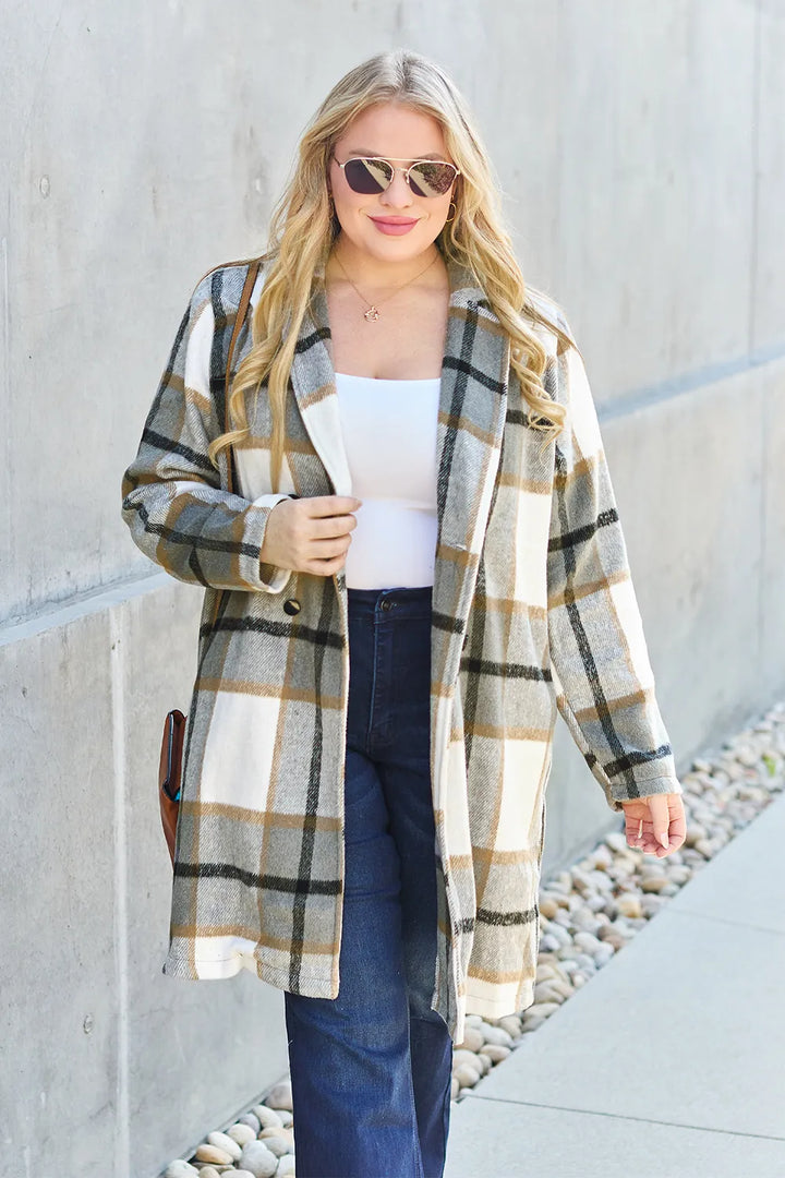 Olive plaid coat worn open over a white top with flare jeans, close framing