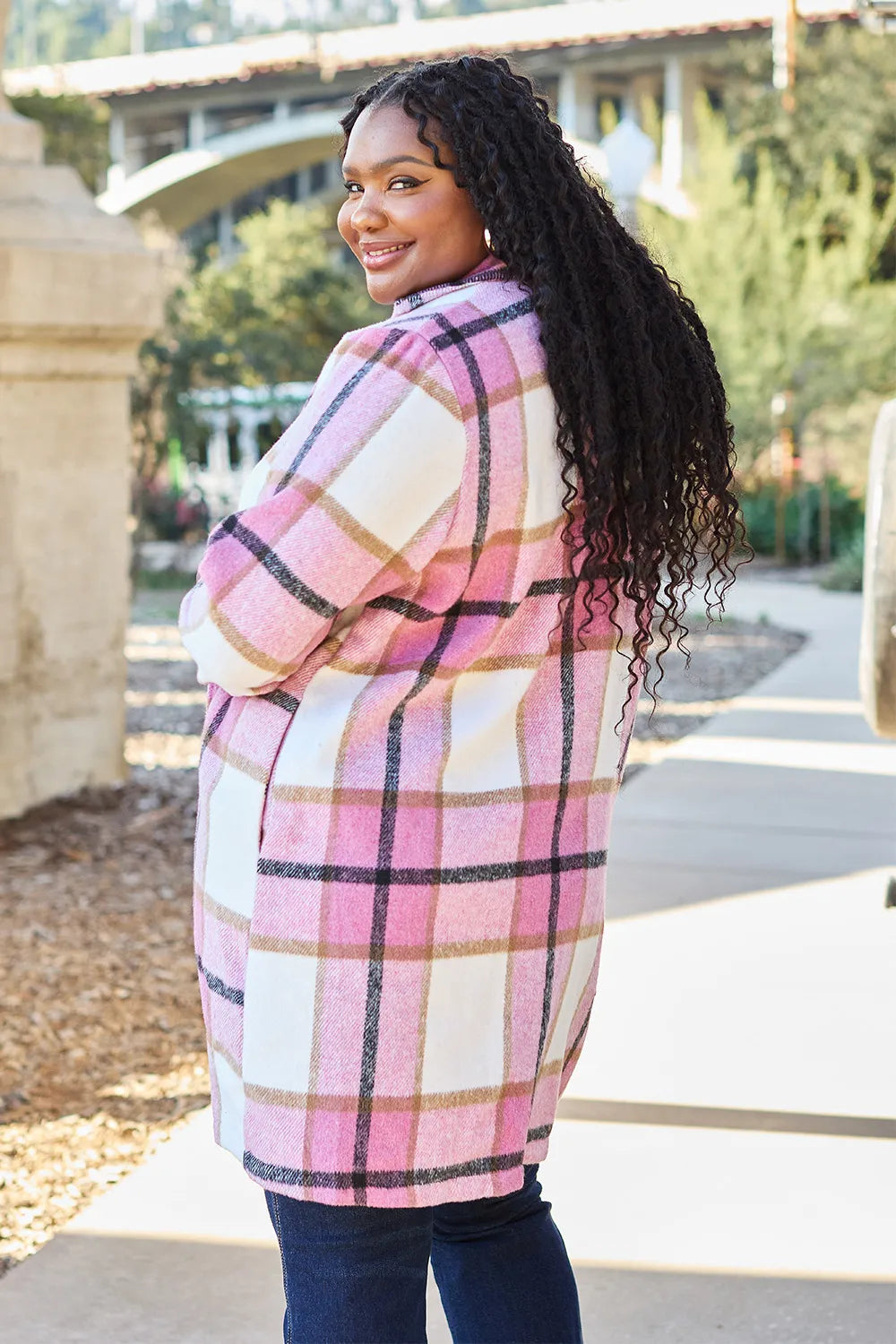 Pink plaid mid length coat in a over the shoulder look, outdoors